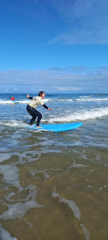 Deelnemer surfkamp 14 jaar surft naar het strand toe