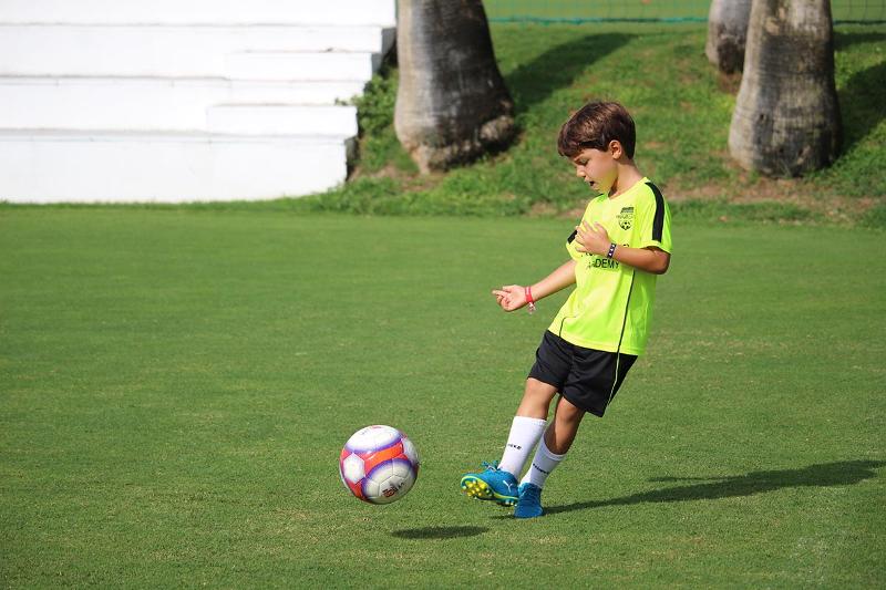 Een jongetje schiet een voetbal tijdens zijn voetbalkamp in Spanje