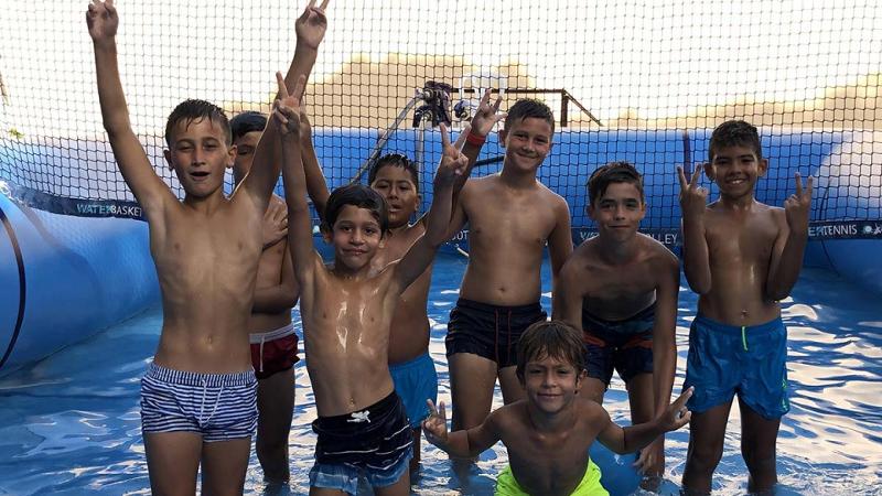 Een groep kinderen staat in een zwembad tijdens een voetbalkamp in Spanje