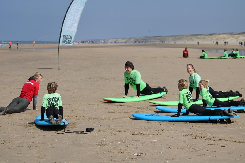 Kinderen krijgen uitleg over surfen van hun begeleiders