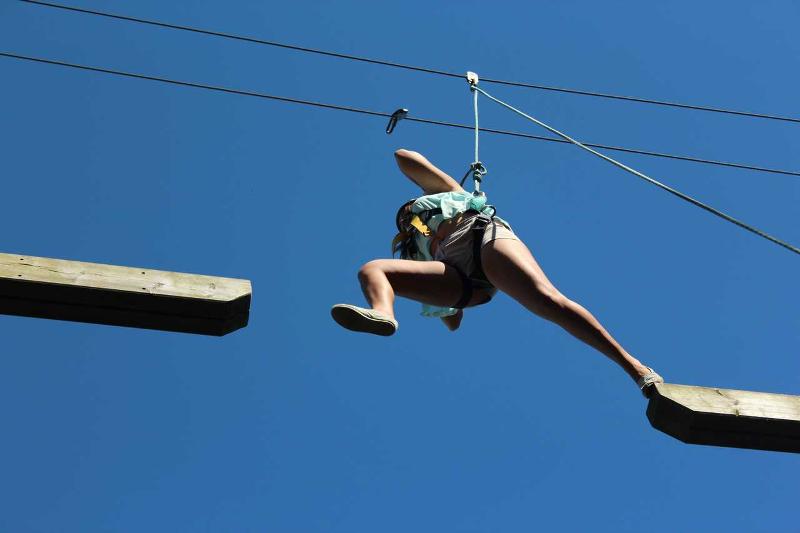 Een deelnemer van een summer camp Portugal springt over een hindernis van onderen