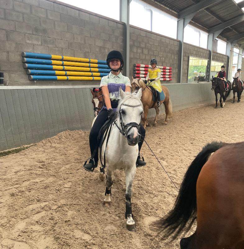 Kind zit op een paard en lacht tijdens een dierenkamp