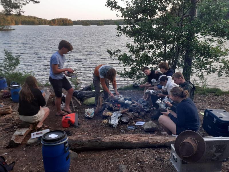 Jongeren maken eten klaar op een kampvuur tijdens een avonturenkamp