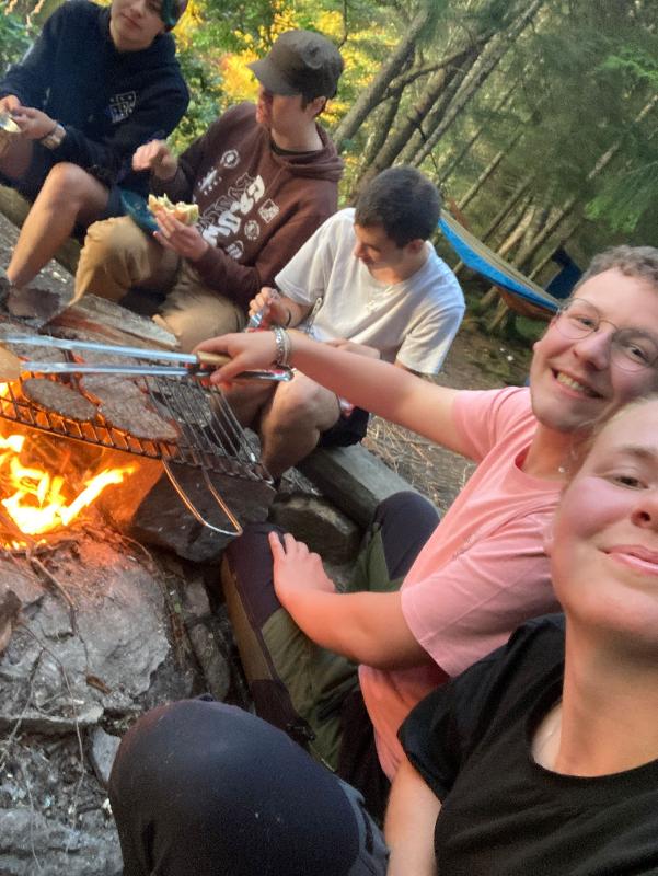 Selfie van een groep jongeren bij een kampvuur tijdens een avonturenkamp