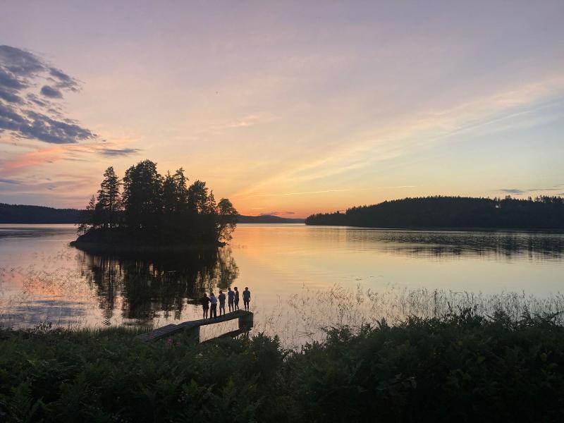 Jongeren staan bij een meer tijdens zonsondergang tijdens een avonturenkamp