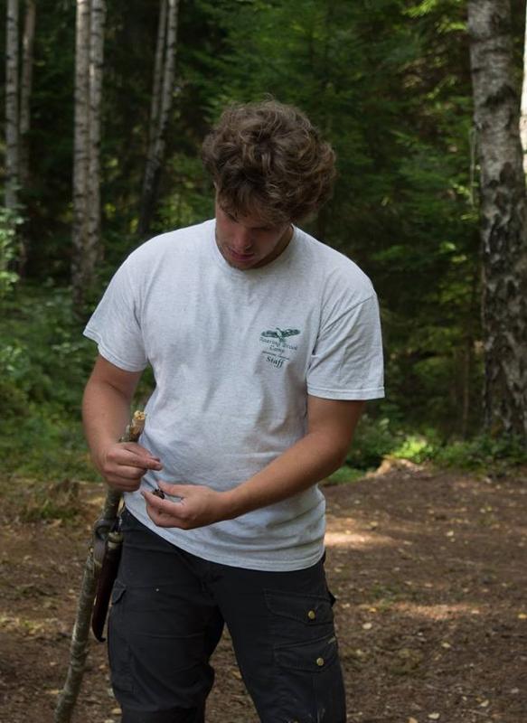 Jongen houdt stok vast in het bos tijdens een avonturenkamp