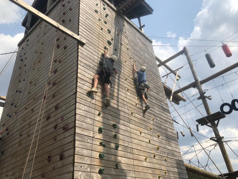 jongeren beklimmen klimtoren met helm op op avonturenkamp ronse
