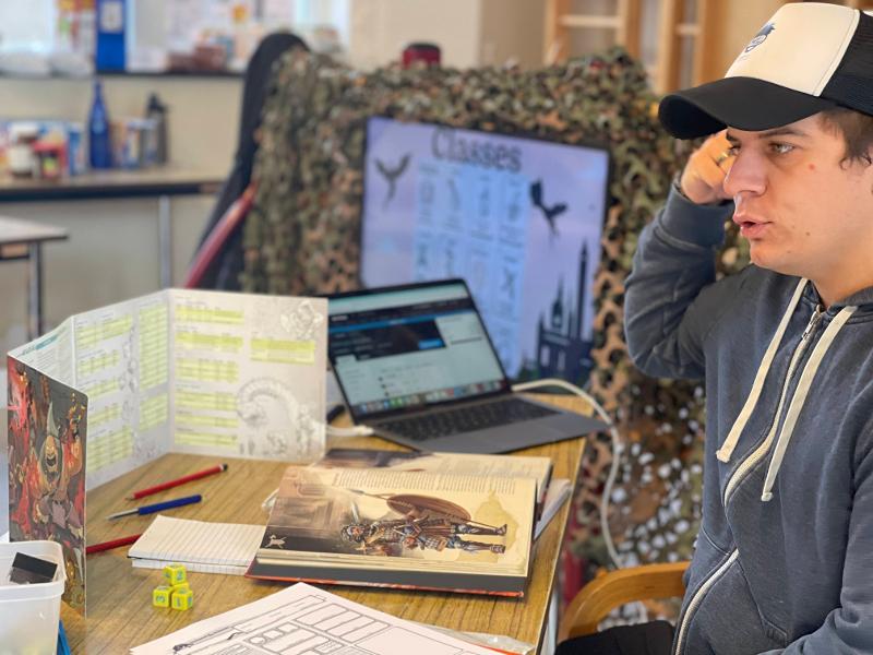 jongen leest boek over het spel op dungeons and dragons zomerkamp