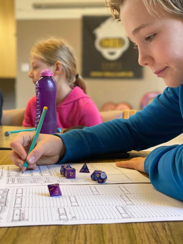 jongen schrijft strategie op papier op dungeons and dragons zomerkamp waregem