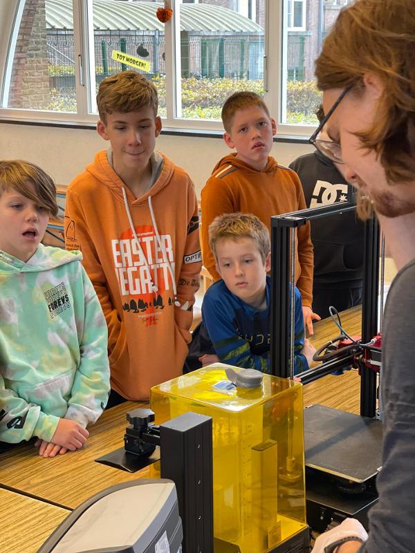 jongens kijken naar man met 3d printer op gamekamp schoten
