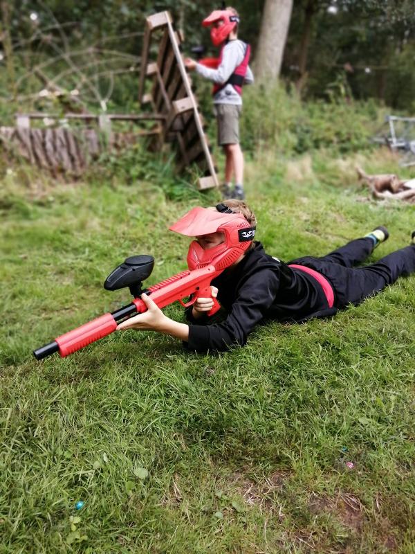 jongen ligt op de grond tijdens paintballen op outdoorkamp schoten