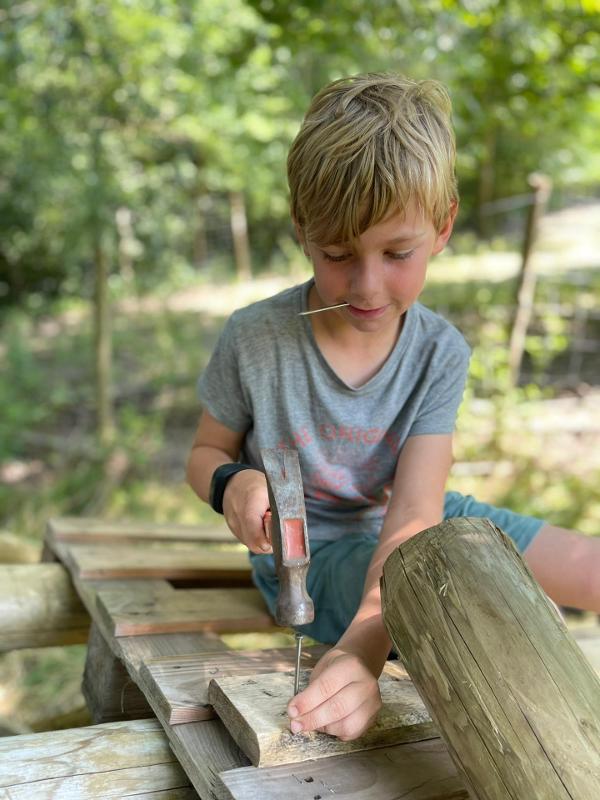 jongen timmert boomhut op survivalkamp schoten