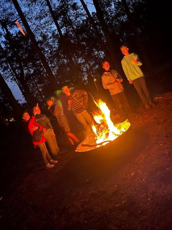 groepje kinderen staan in het donker bij kampvuur op watersportkamp waregem