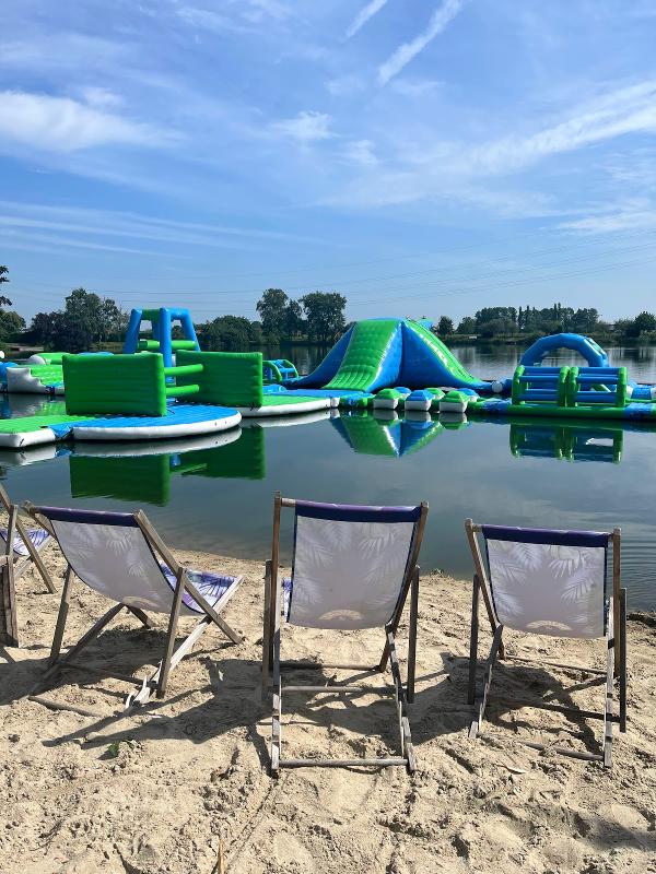 strandstoelen bij het meer met opblaasattractie op watersportkamp waregem