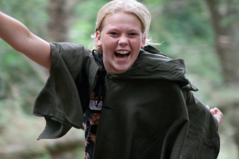 meisje lacht in het bos op avonturen-gamekamp