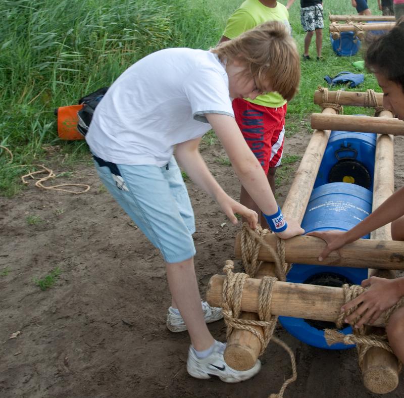 meisje knoopt touw om vlot te bouwen op avonturen-gamekamp