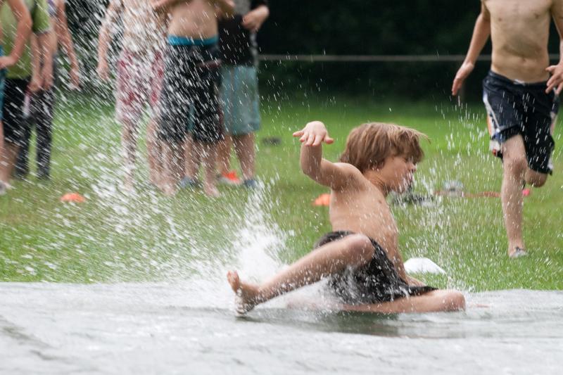 jongen schuift over waterbaan op avonturen-gamekamp
