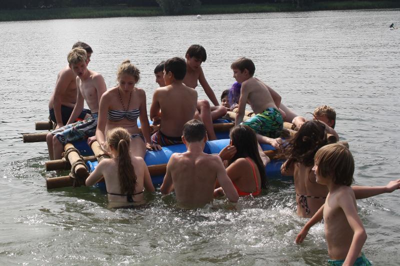 jongeren varen op vlot in het water op game en avonturenkamp