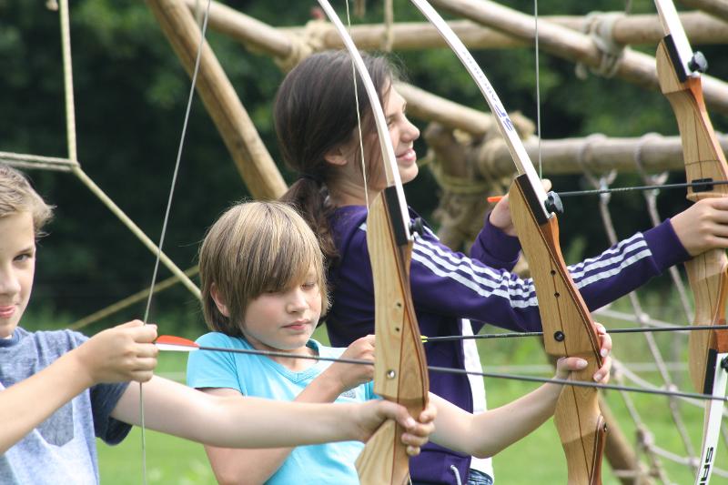 jongens en meisje houden pijl en boog vast op game en avonturenkamp