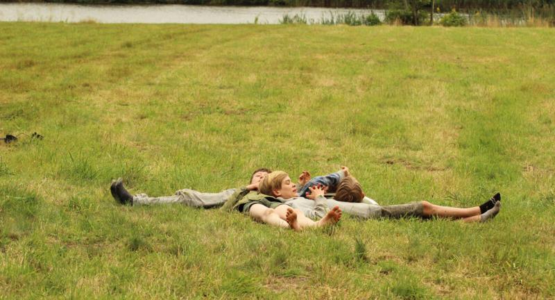 Kinderen chillen in het gras tijdens een natuurkamp