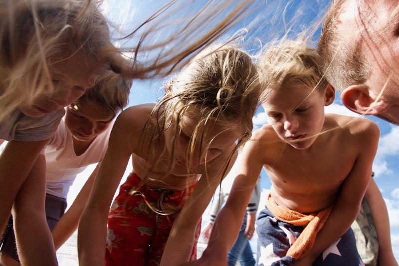 Kinderen zoeken naar schelpen op het strand tijdens een natuurkamp