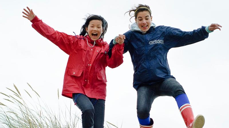 Twee kinderen springen door het gras tijdens een natuurkamp