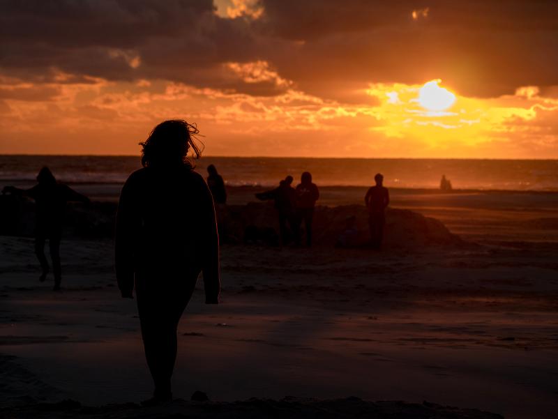 Jongeren op het strand tijdens de zonsondergang 