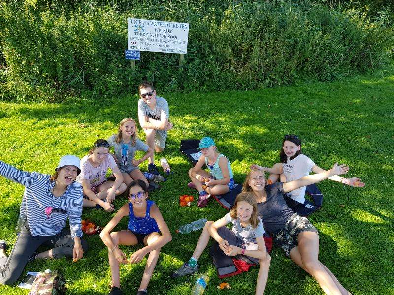 groepje kinderen zit op het gras op zeilkamp bij leiden