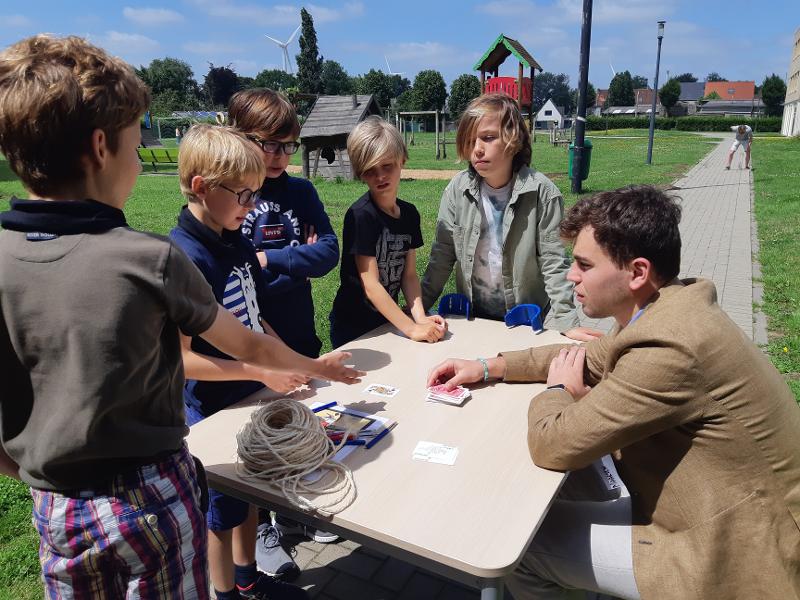jongens staan rond een tafel buiten tijdens musical kamp
