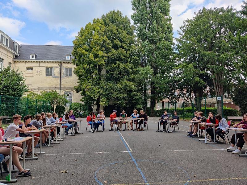 Deelnemers aan taalkamp belgië volgen buiten lessen in een cirkel op de campus