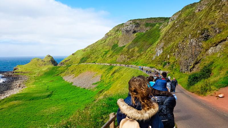 Jongeren wandelen over een weg bij een heuvel tijdens een taalreis engels