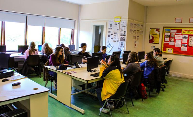 Jongeren zitten in een lokaal met computers tijdens een taalreis engels