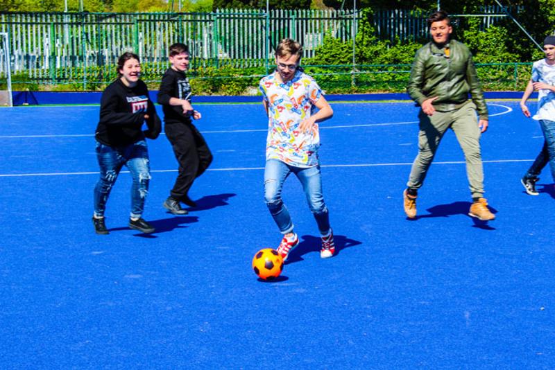 Jongeren zijn aan het voetballen op een blauw veld tijdens een taalreis engels
