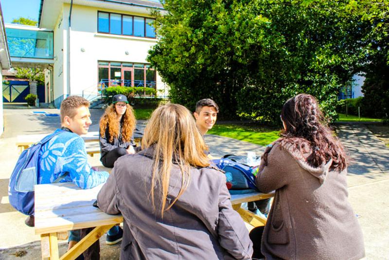 Jongeren zitten aan een picknick tafel tijdens een taalreis engels