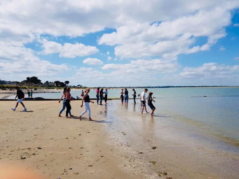 Jongeren lopen over het strand naar het water tijdens een taalreis engels