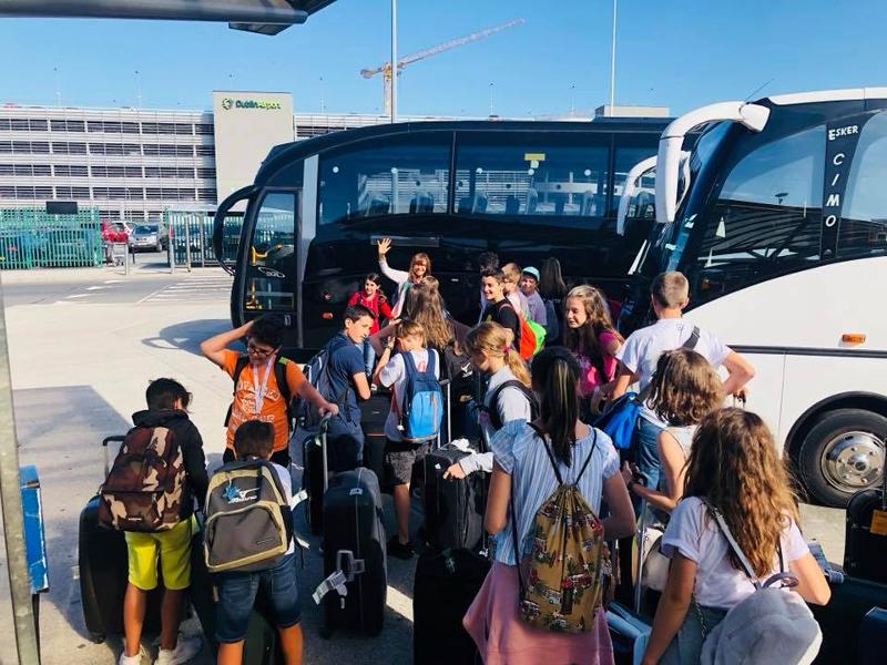 Jongeren staan bij twee bussen te wachten tijdens een taalreis engels