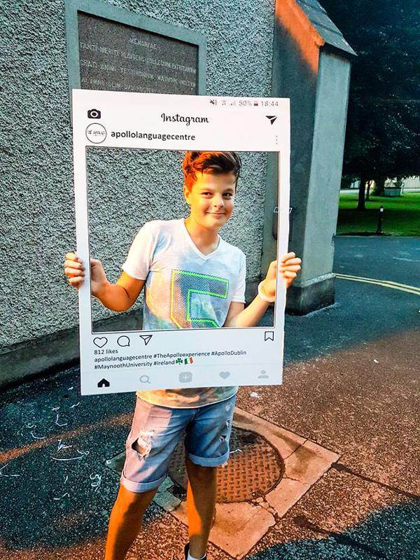 Een jongen met een papieren Instagram cut out tijdens een taalreis engels