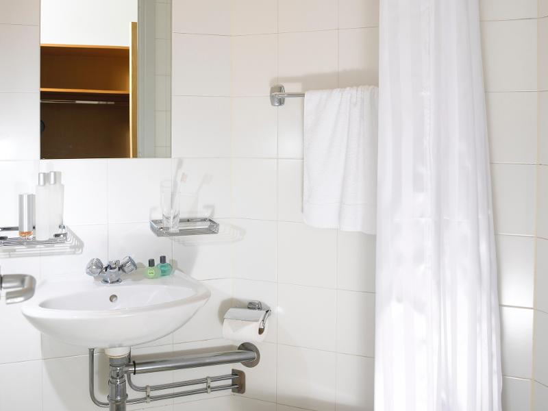 Een wastafel, handdoek en douchegordijn in een badkamer tijdens een taalreis engels