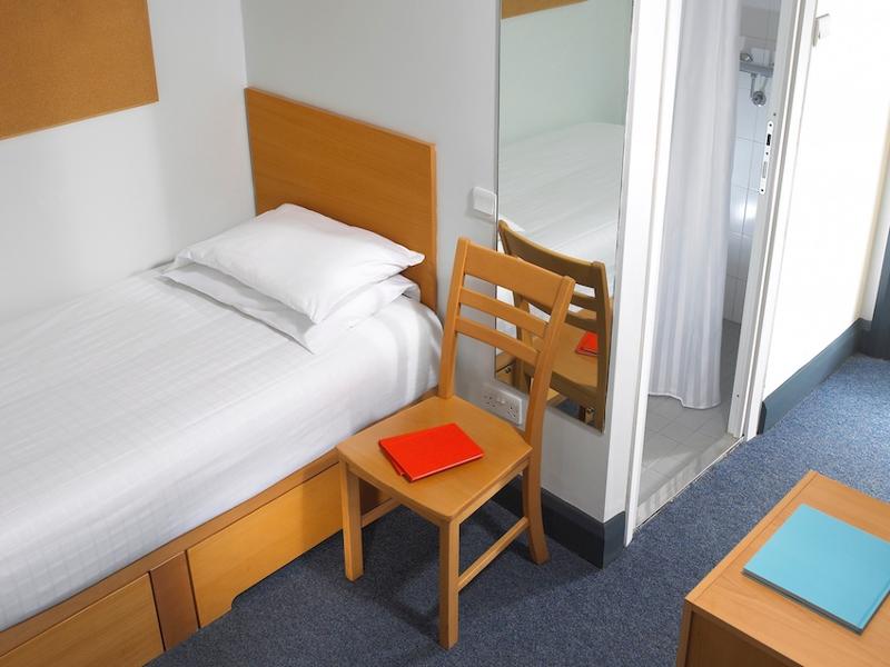 Een slaapkamer met een bed en stoel tijdens een taalreis engels