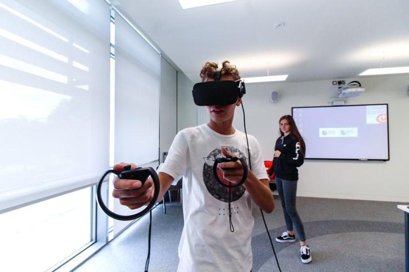 Een jongen met VR headset en controllers tijdens een taalreis engels