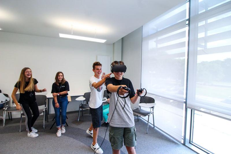Een groep jongeren met een jongen met een VR headset tijdens een taalreis engels