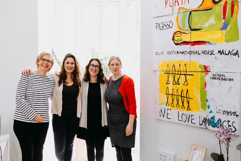 Een groepsfoto van docenten bij een muur met schilderijen tijdens een taalreis spaans