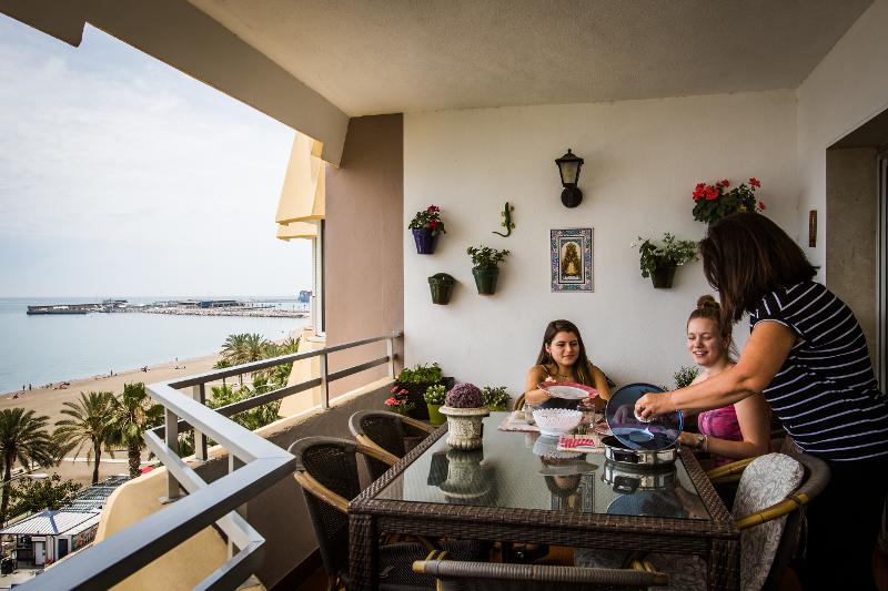 Jongeren eten ontbijt op een balkon met uitzicht op zee tijdens een taalreis spaans