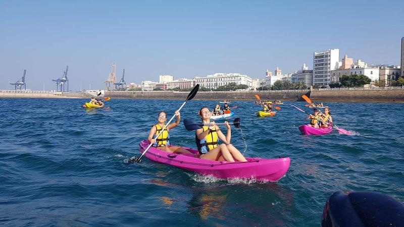 Jongeren kayakken op zee in roze boten tijdens een taalreis spaans