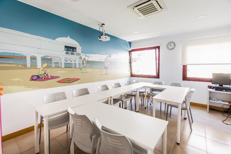 Een klaslokaal met tafels, stoelen en een poster tijdens een taalreis spaans