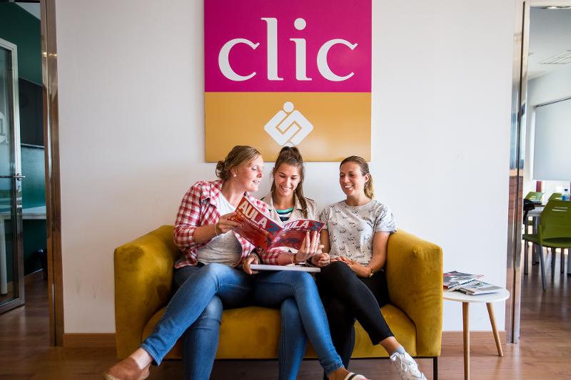 Drie meiden lezen een tijdschrift op een bank tijdens een taalreis spaans