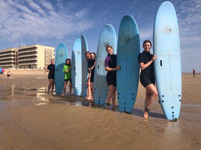 Jongeren poseren met hun surfboards op het strand tijdens een taalreis spaans