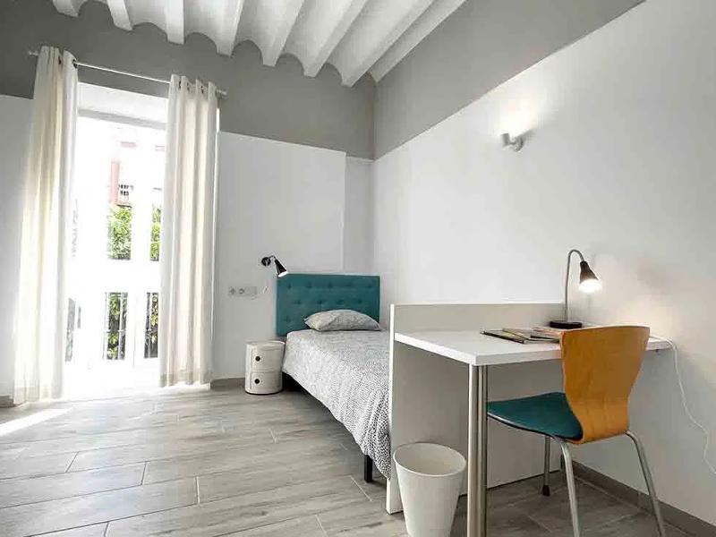 Een slaapkamer met bureau en bed tijdens een taalreis spaans