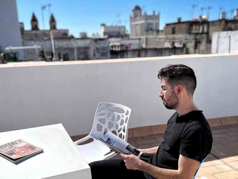 Een jongen leest een tijdschrijft op een dakterras tijdens een taalreis spaans
