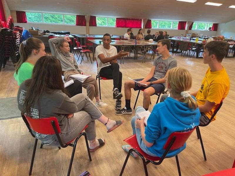 Een aantal deelnemers aan een summer camp English zitten in een kring met de begeleider en krijgen uitleg